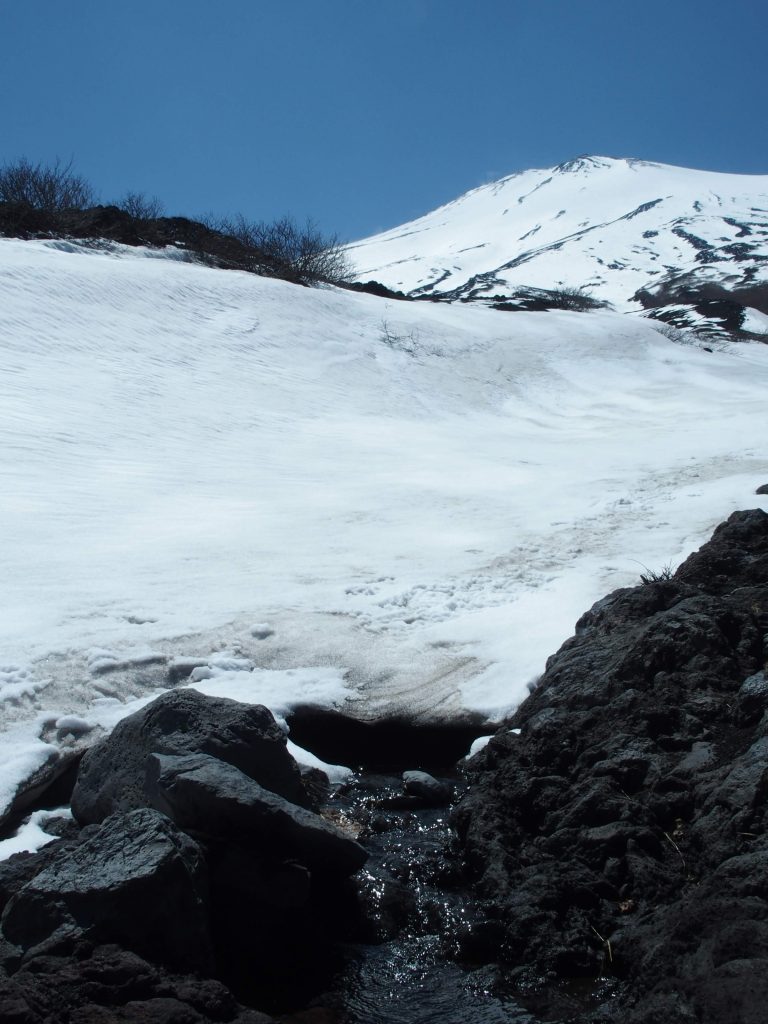 大きな雪渓の下をくぐり抜けて